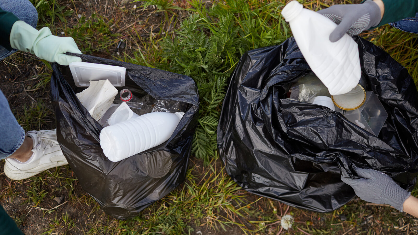 Two bags being filled with household waste during a trash removal